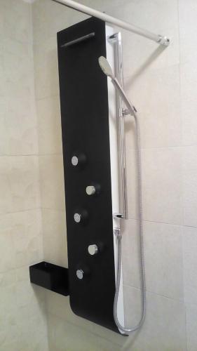 a shower with a black wall with a shower head at Káli Apartman in Bakonybél