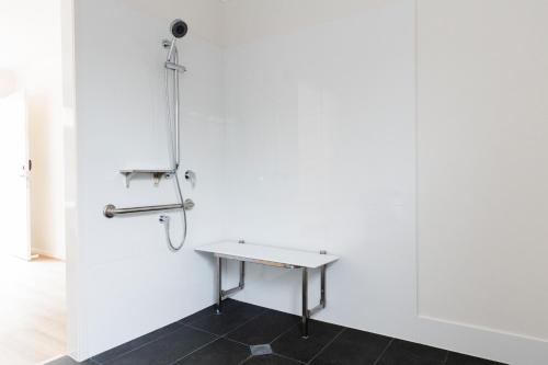 a white wall with a table and a shower at Petrie Mill Motel in Petrie
