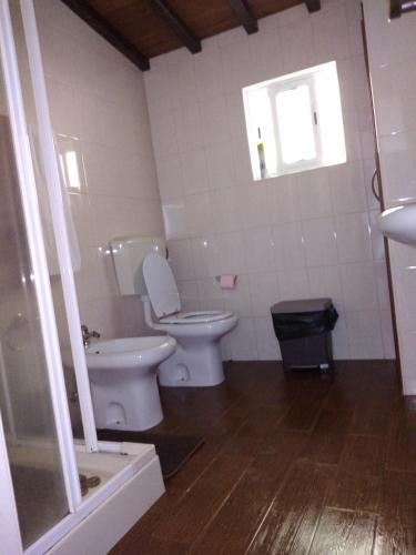 a bathroom with a toilet and a sink and a window at Casa dos Valentes in Santo Espírito