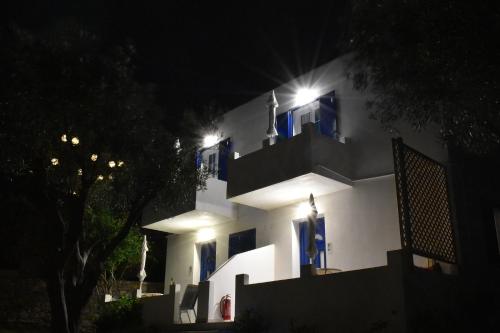 a white building with blue windows at night at Litus Studios Syros in Megas Yialos-Nites