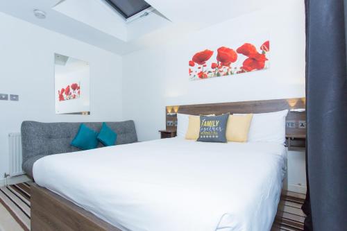a bedroom with a large white bed with blue accents at Langley Guest House Nr Pinewood Studios in Slough