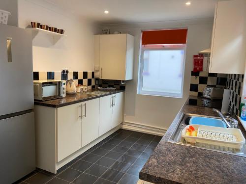 a small kitchen with white cabinets and a sink at 39 Cowley Road in Liverpool