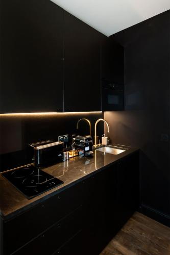 - une cuisine noire avec évier et cuisinière dans l'établissement LE MARAIS PRESTIGE Luxueux - Cosy - Wifi, à Paris