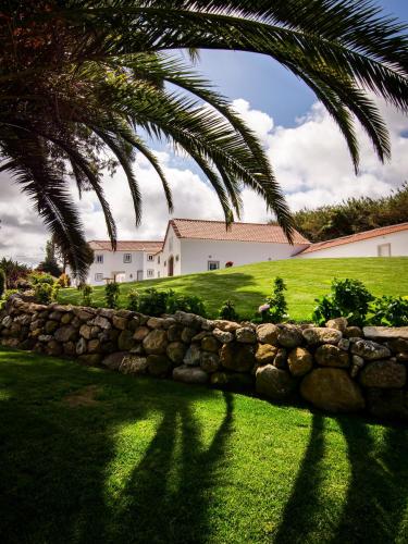 a palm tree and a stone wall in front of a house at Quinta Pedra Firme in Sintra