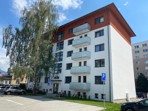 un edificio bianco e arancione con parcheggio di FLEXIHOME sk - Bellova - Brand New - Neftflix - Private Parking a Liptovský Mikuláš