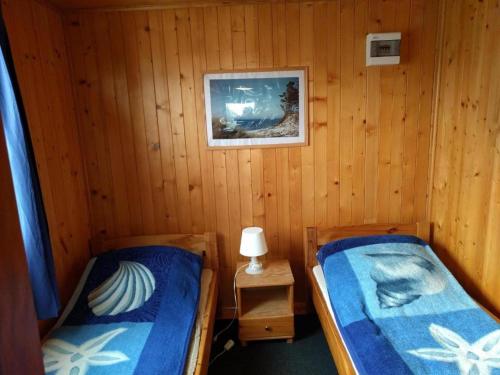 two beds in a room with wooden walls at Domek Muszelka in Karwia