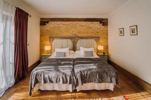 a bedroom with a large bed and a brick wall at Finca Monasterio in San Martín del tesorillo