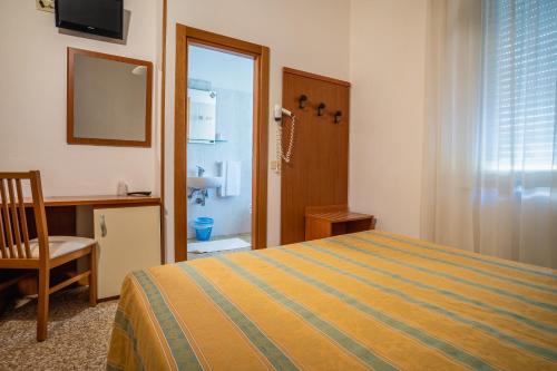 a bedroom with a bed and a desk and a mirror at Hotel Happy in Milano Marittima