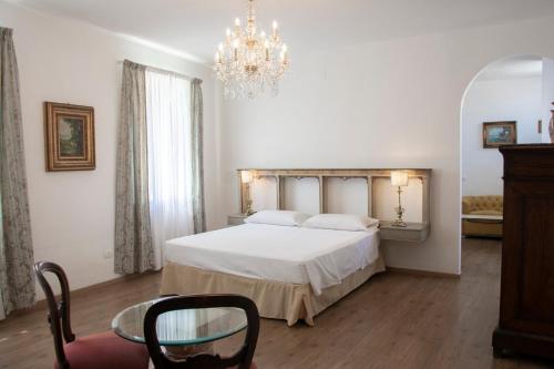 sypialnia z białym łóżkiem i żyrandolem w obiekcie Il Palazzetto w Sorrento