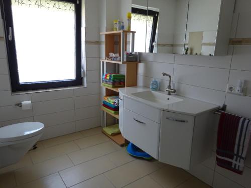 uma casa de banho com um lavatório, um WC e uma janela. em Ferienwohnung Schwiemann, Erdgeschoss em Cadenberge