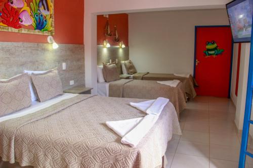 a hotel room with two beds and a red door at Kaliman Pousada in Ubatuba