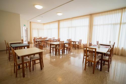 a dining room with tables and chairs and windows at Hotel Happy in Milano Marittima