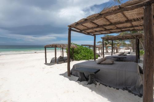two beds on a beach with the ocean in the background at NEST Tulum in Tulum