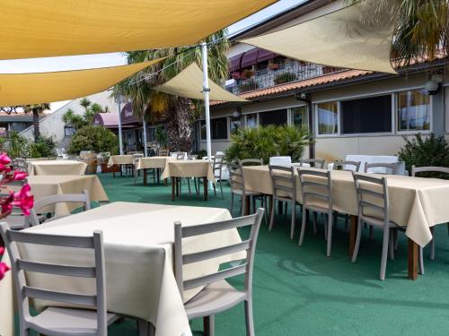 a restaurant with white tables and chairs and yellow umbrellas at Hotel La Rosa Dei Venti in Albinia