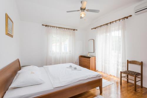 a bedroom with a bed with a ceiling fan and a chair at Historic center Hvar town- a few steps from the main square in Hvar