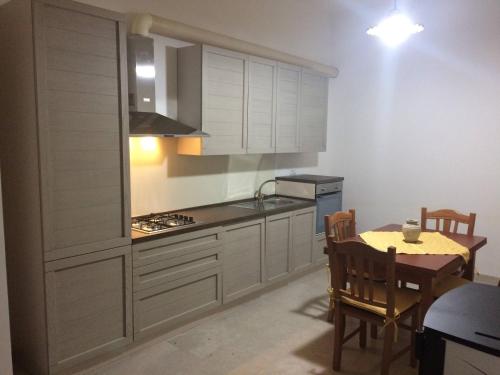 una cocina con armarios blancos y una mesa con comedor. en Casa Giò, en Cisternino