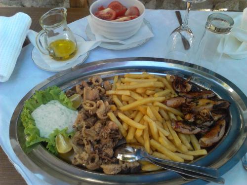 a plate of food with french fries and meat at Guest House Frane in Pag