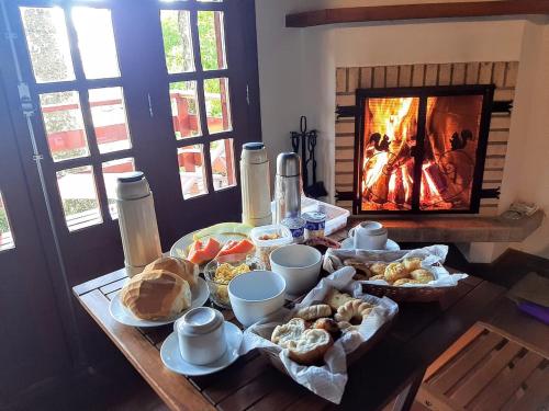 a table with bread and pastries and a fireplace at Hospedagem Spa da Alma in Monte Verde