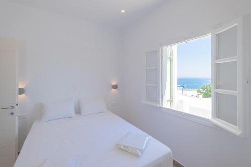 a white bedroom with a large window with the ocean at Lorenzo Studios and Suites Paros in Naousa