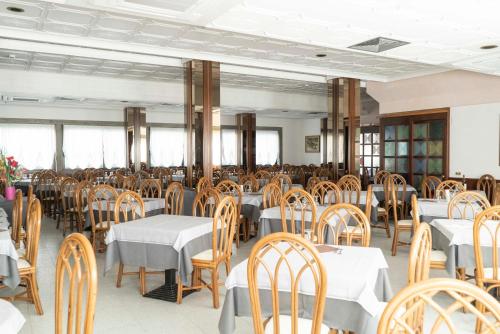 una sala da pranzo con tavoli e sedie di Hotel President a Lido di Jesolo