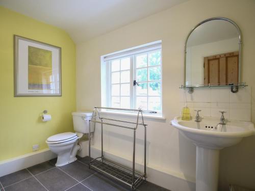 a bathroom with a sink and a toilet and a mirror at Kettle Cottage in Chipping Campden