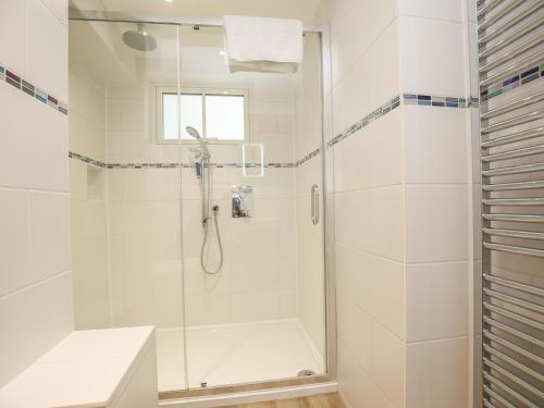 a white bathroom with a shower with a glass door at 5 Burford Mews in Burford