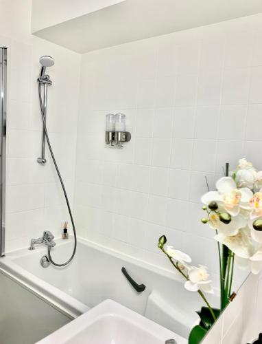 La salle de bains est pourvue d'un lavabo et d'une baignoire fleurie. dans l'établissement L'appart Moulin des Thermes Metz, à Metz