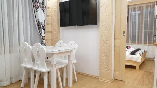 a white dining room with white chairs and a table at Villa Fortuna - Regionalne apartamenty & SPA - Sauna, Grill, Jacuzzi z widokiem na Tatry in Zakopane