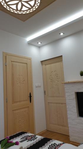 two wooden doors in a room with a fireplace at Villa Fortuna - Regionalne apartamenty & SPA - Sauna, Grill, Jacuzzi z widokiem na Tatry in Zakopane