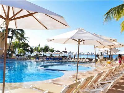 a swimming pool with white chairs and umbrellas at VILLA PARA 5P 4A 1M dentro del Hotel a un lado del Krystal IXTAPA Con Playa WiFi in Ixtapa