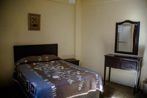 a bedroom with a bed and a dresser and a mirror at HOTEL POSADA DEL CORTEZ in La Paz