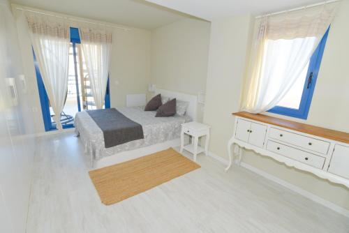a bedroom with a bed and a dresser and windows at Luxury penthouse,first line in Alicante