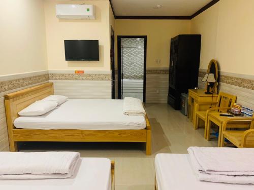 a bedroom with two beds and a tv on the wall at Mekong Rose Hotel in Can Tho