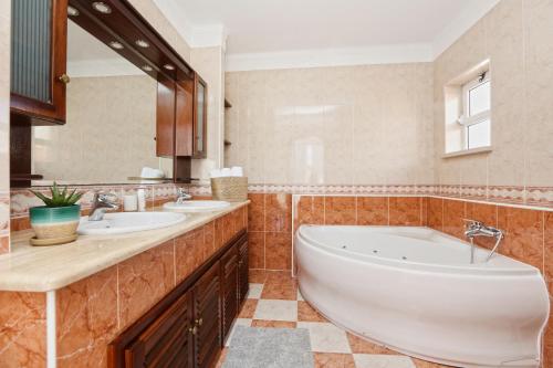 Un baño con dos lavabos y una bañera grande. en Sunrise Terrace Peniche, en Peniche