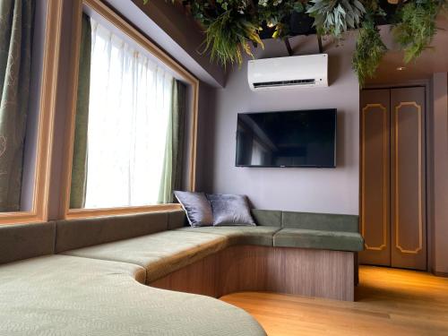 uma sala de espera com um banco e uma televisão em THE WARDROBE Hotel Shimokitazawa em Tóquio