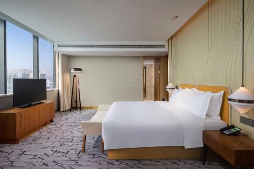 a bedroom with a large white bed and a television at Holiday Inn Tianjin Xiqing by IHG in Tianjin