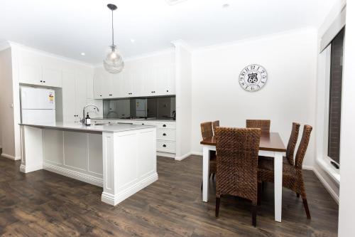 a kitchen with white cabinets and a table and chairs at Glen’s Inner City Escape - CBD Central in Wagga Wagga