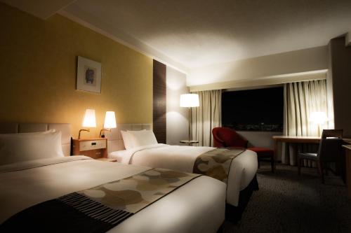 a hotel room with two beds and a desk at Hotel New Otani Hakata in Fukuoka