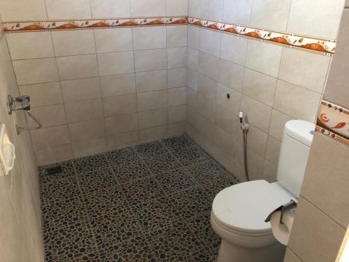 a bathroom with a toilet and a tiled floor at Kerti Beach Bungalow and Restaurant in Padangbai