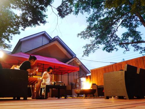 Guesthouse Curry Village في هوكوتو: يجلس شخصان على طاولة تحت مظلة