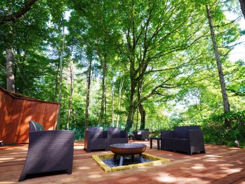 eine Terrasse mit Stühlen, einem Tisch und Bäumen in der Unterkunft Guesthouse Curry Village in Hokuto