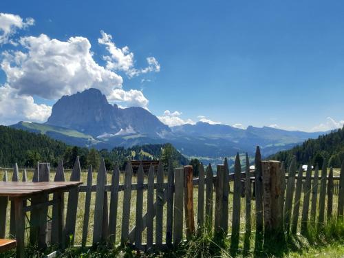 a fence with a table and mountains in the background at Garni Franca b&b in Selva di Val Gardena