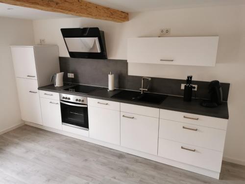 een keuken met witte kasten en een zwart aanrecht bij Traumhaftes Apartment zentral in Bad Berleburg in Bad Berleburg