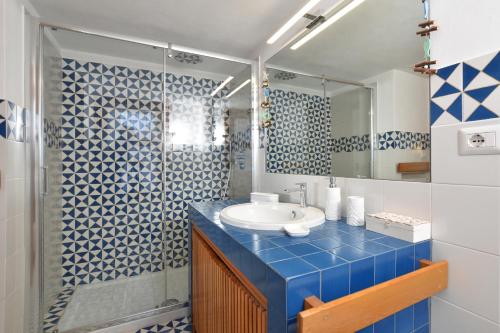 y baño azul con lavabo y ducha. en Villa Ada - Happy Rentals, en Ansedonia