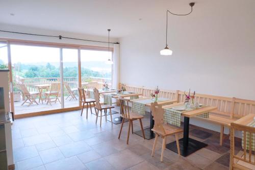 a restaurant with wooden tables and chairs and a large window at Bauernhof Gschmeidler in Sankt Johann im Saggautal