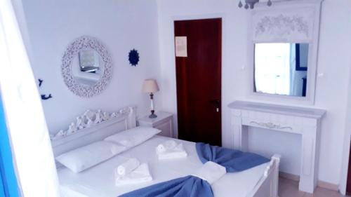 a white bedroom with a bed and a mirror at Christos Rooms in Palaiochóra