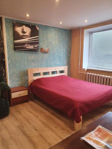 a bedroom with a bed with a red bedspread at Apartament Erfolg 3 in Daugavpils