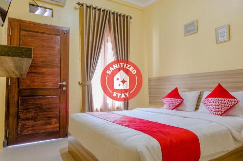 a bedroom with a large bed with red and white pillows at Capital O 1566 El Reyshi Family Residence in Banyuwangi
