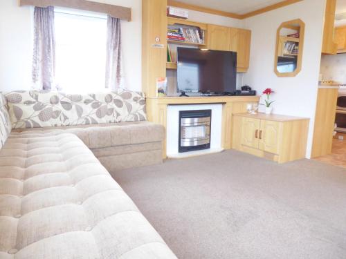 a living room with a couch and a television at Beachside, Family-friendly, WiFi, 8 berth Caravan 158 in Ingoldmells