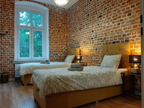 2 Betten in einem Zimmer mit Ziegelwand in der Unterkunft Apartamenty Lubin - Loft in Lubin